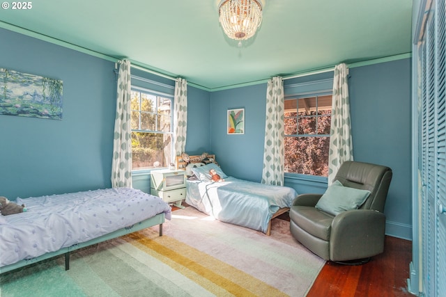 bedroom with wood finished floors, baseboards, and crown molding