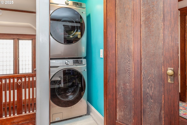 laundry area with stacked washer / drying machine and baseboards