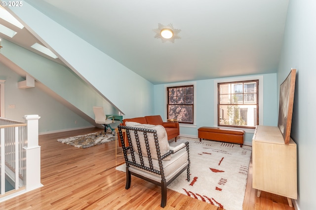 sitting room featuring a skylight, wood finished floors, vaulted ceiling, an upstairs landing, and baseboards