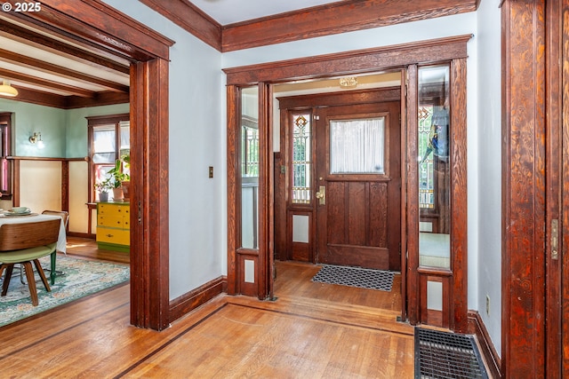 entryway with light wood-style flooring, baseboards, and crown molding