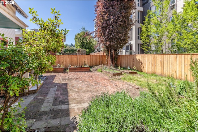 fenced backyard with a vegetable garden and a patio area