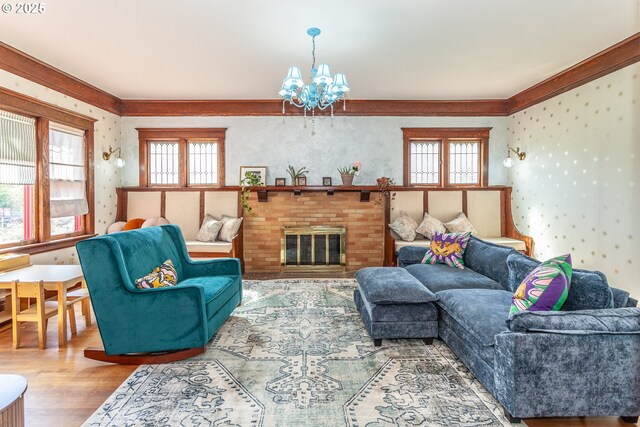 living area with ornamental molding, wallpapered walls, wood finished floors, a chandelier, and healthy amount of natural light