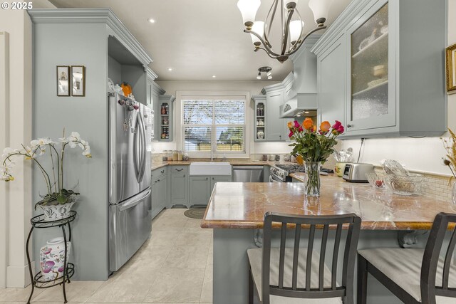 kitchen featuring appliances with stainless steel finishes, a peninsula, a sink, recessed lighting, and gray cabinetry