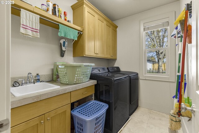 laundry room featuring washing machine and dryer, cabinet space, and light tile patterned floors