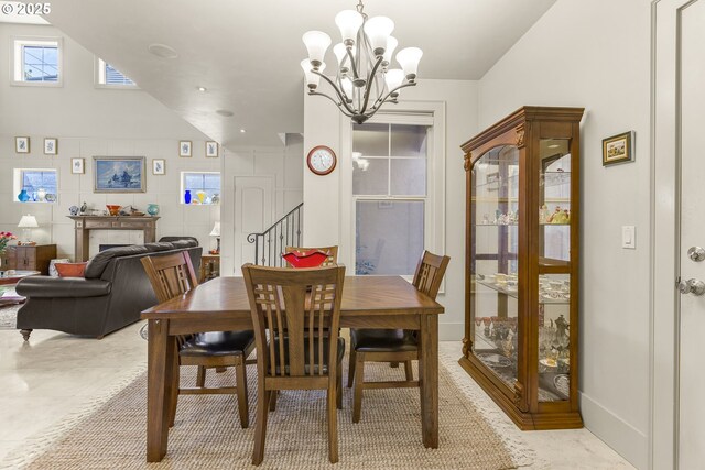 dining area featuring a chandelier, a tile fireplace, and stairway