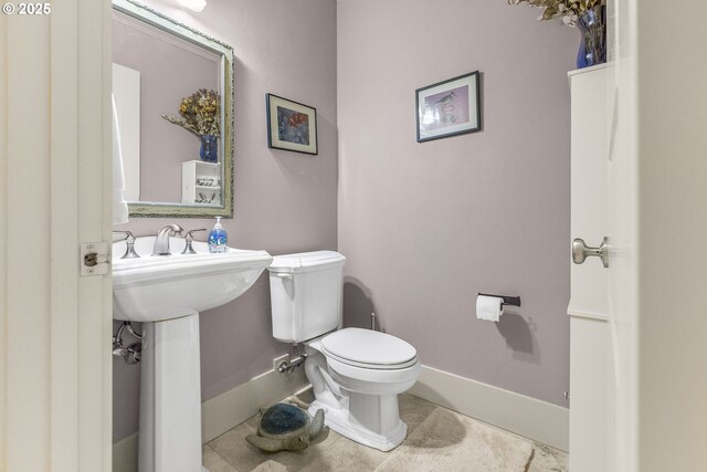 half bath featuring toilet and baseboards