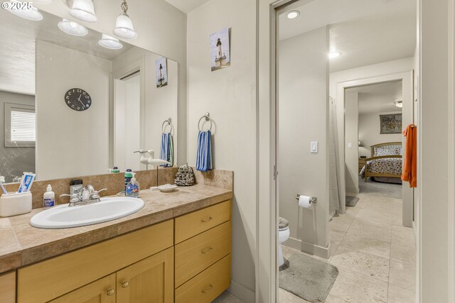 bedroom with light carpet, a closet, ensuite bathroom, and baseboards