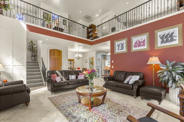 living area with stairs, a chandelier, a towering ceiling, tile patterned flooring, and arched walkways