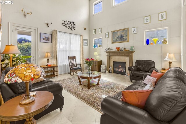 living area featuring a towering ceiling, a tile fireplace, and light tile patterned floors