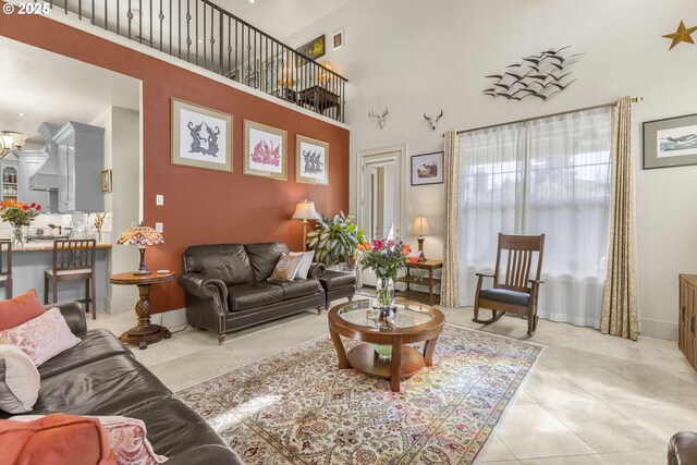 living room with a towering ceiling and light tile patterned floors