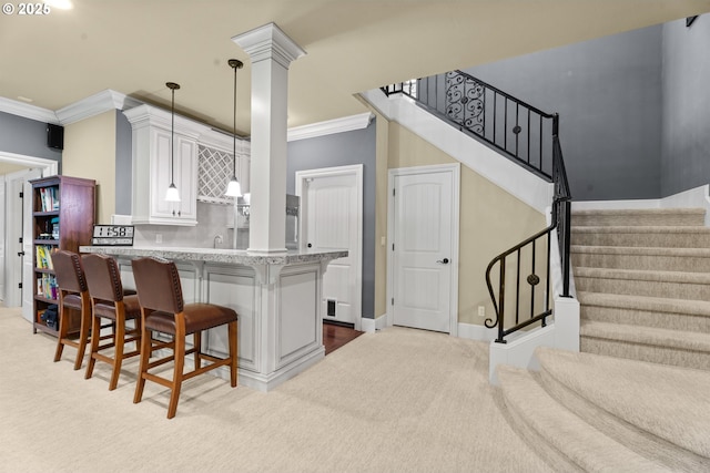 9641 SE Nicholas Dr, Happy Valley, OR 97086 - kitchen with crown molding, a kitchen breakfast bar, light colored carpet, white cabinetry, and pendant lighting