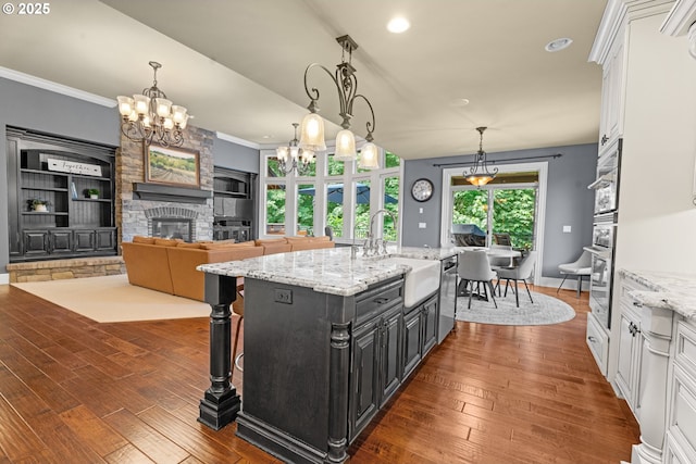 9641 SE Nicholas Dr, Happy Valley, OR 97086 - kitchen with a chandelier, white cabinetry, a fireplace, stainless steel appliances, and dark wood-style floors