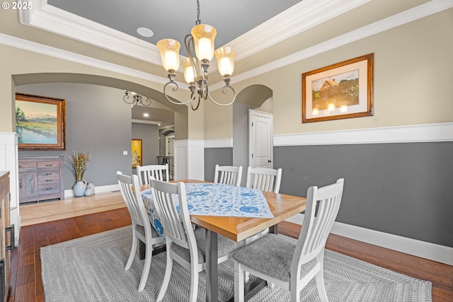 9641 SE Nicholas Dr, Happy Valley, OR 97086 - dining room featuring arched walkways, a tray ceiling, a chandelier, ornamental molding, and dark wood finished floors