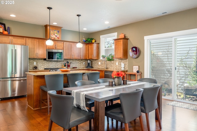 12146 SW Palermo St, Wilsonville, OR 97070 - kitchen featuring stainless steel appliances, a center island, tasteful backsplash, dark wood-style floors, and brown cabinets