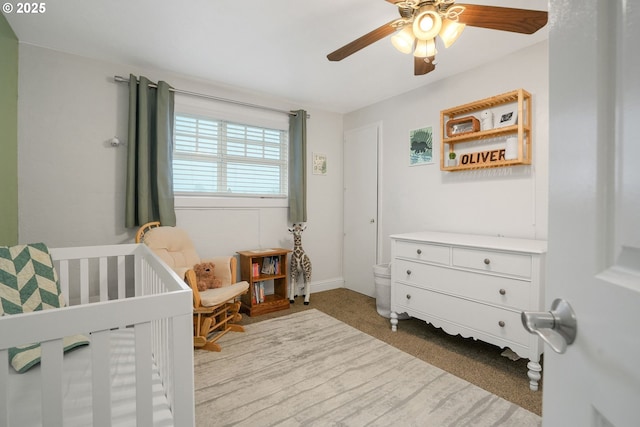 bedroom with ceiling fan, light colored carpet, and a nursery area