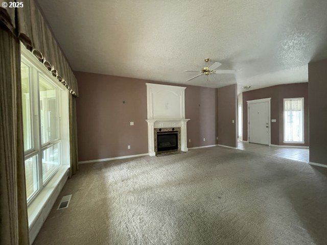 15732 NE Russell St, Portland, OR 97230 - unfurnished living room with light carpet, baseboards, a fireplace with flush hearth, ceiling fan, and a textured ceiling