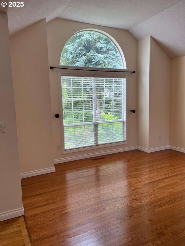 3553 NW 163rd Ct, Beaverton, OR 97006 - unfurnished living room featuring vaulted ceiling, wood finished floors, a textured ceiling, and healthy amount of natural light