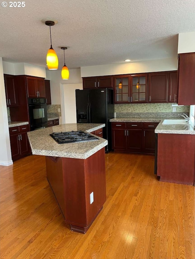 3553 NW 163rd Ct, Beaverton, OR 97006 - kitchen with black appliances, a textured ceiling, light wood-style flooring, a center island, and light countertops