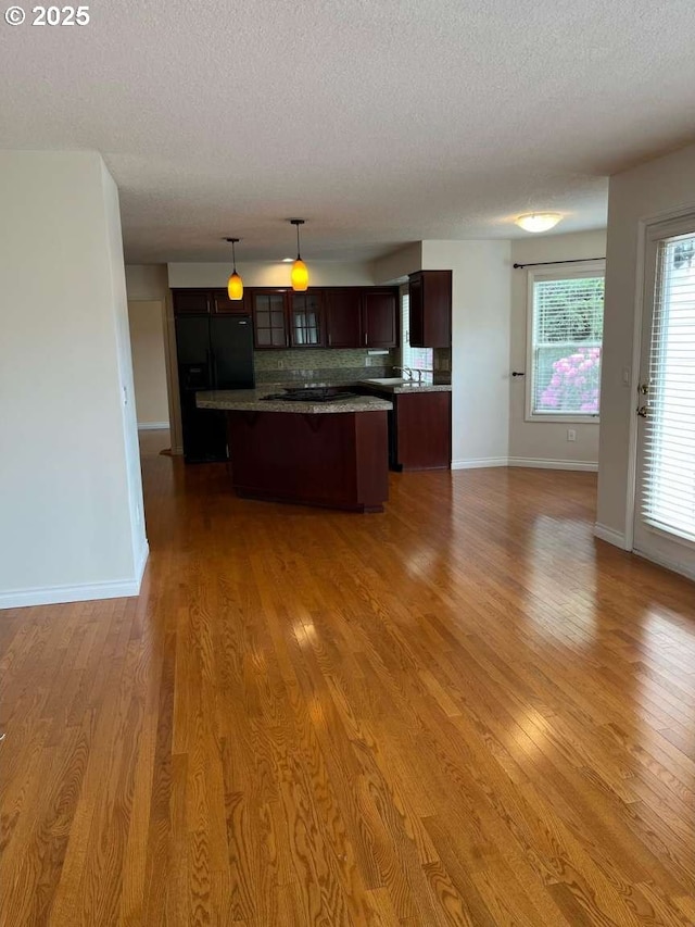 3553 NW 163rd Ct, Beaverton, OR 97006 - kitchen featuring black fridge with ice dispenser, a center island, light wood-type flooring, open floor plan, and a textured ceiling