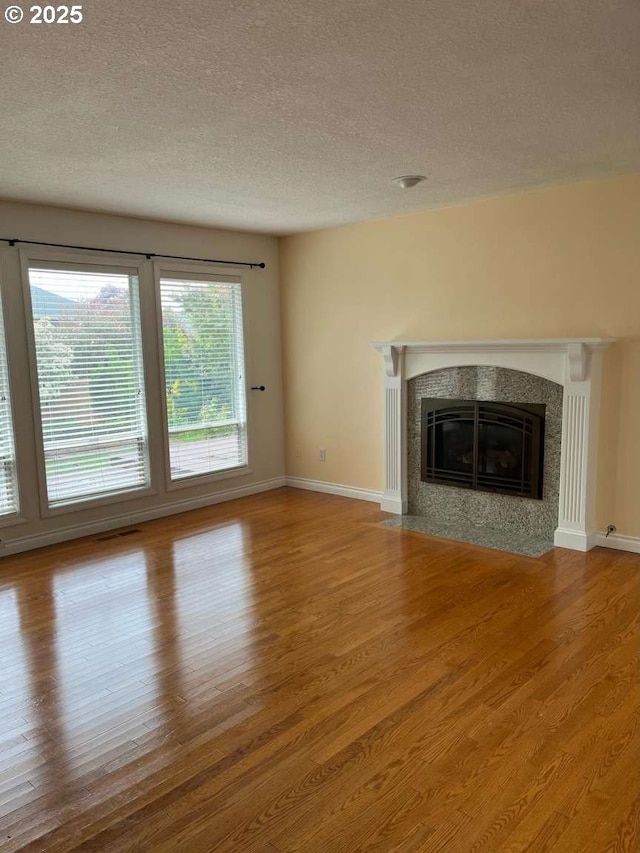 3553 NW 163rd Ct, Beaverton, OR 97006 - unfurnished living room with wood finished floors, a textured ceiling, and a high end fireplace