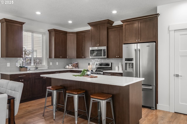 2522 S Lydia Loop, Hubbard, OR 97032 - kitchen with appliances with stainless steel finishes, a kitchen bar, backsplash, recessed lighting, and a textured ceiling