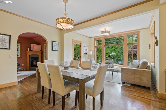 17367 Canal Cir, Lake Oswego, OR 97035 - dining space featuring arched walkways, baseboards, crown molding, a lit fireplace, and wood finished floors