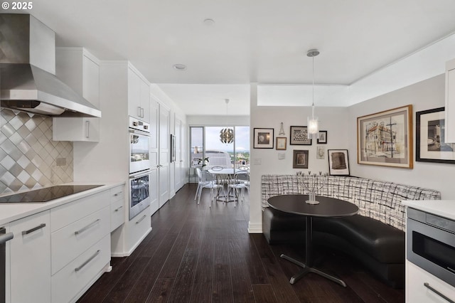 kitchen with wall chimney exhaust hood, appliances with stainless steel finishes, backsplash, and light countertops