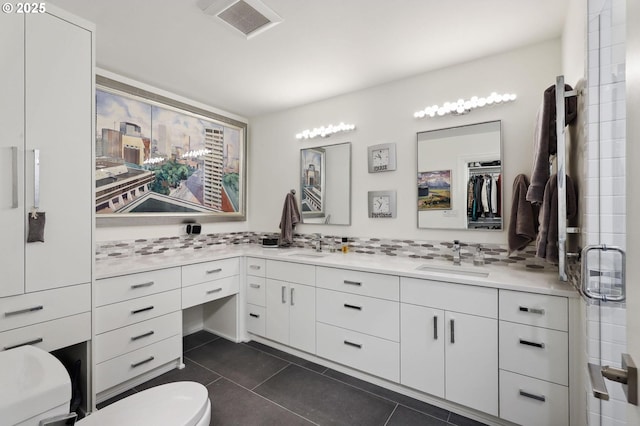 bathroom featuring toilet, tile patterned flooring, and double vanity