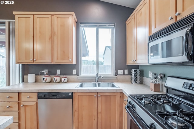 kitchen with a sink, light brown cabinets, and stainless steel appliances