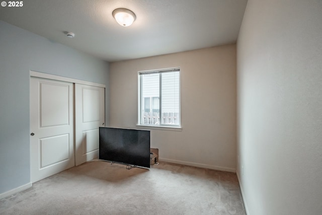 unfurnished bedroom featuring carpet floors, baseboards, and a closet