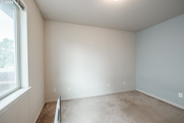 unfurnished room featuring a healthy amount of sunlight, baseboards, a baseboard radiator, and light colored carpet