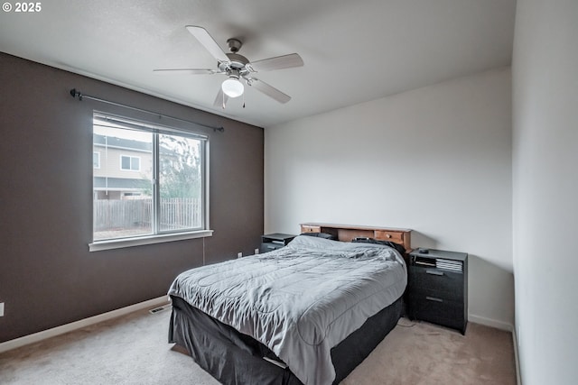 bedroom with baseboards, light carpet, a ceiling fan, and visible vents