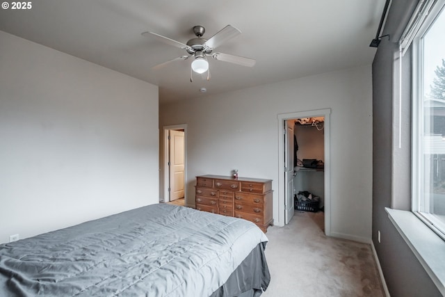 bedroom featuring light carpet, a ceiling fan, baseboards, a spacious closet, and a closet
