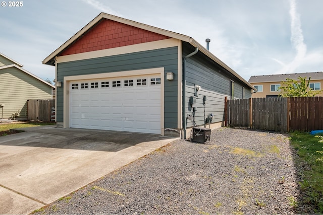 garage featuring fence and gravel driveway