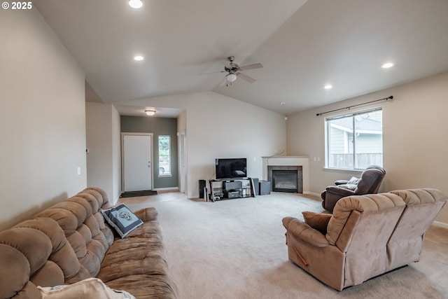 living room with light colored carpet, a fireplace, a ceiling fan, baseboards, and vaulted ceiling