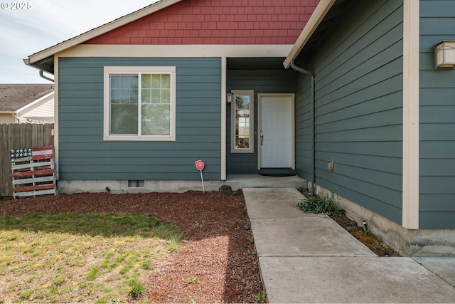 view of exterior entry with crawl space and fence