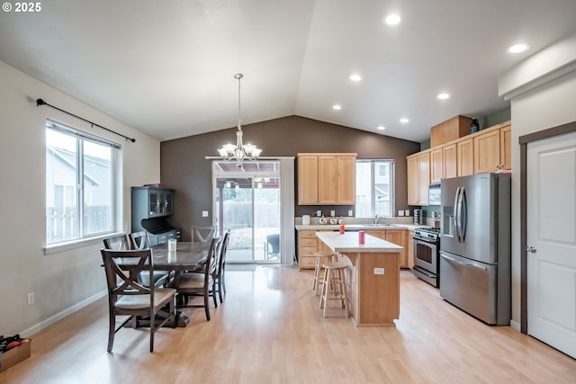 kitchen with a kitchen island, light brown cabinetry, appliances with stainless steel finishes, light countertops, and lofted ceiling