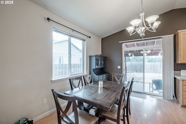 dining space featuring an inviting chandelier, light wood-style flooring, baseboards, and vaulted ceiling