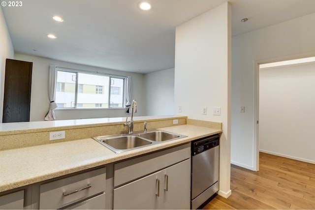 kitchen with a sink, light wood-type flooring, light countertops, and stainless steel dishwasher