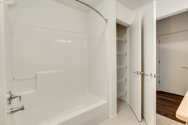 bathroom with shower / bath combination, a walk in closet, and tile patterned floors