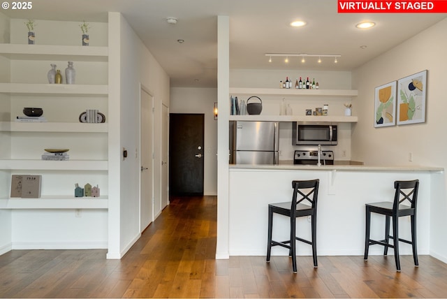 kitchen featuring stainless steel appliances, dark wood-type flooring, a breakfast bar area, and open shelves