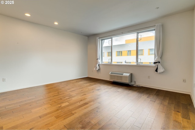 unfurnished room featuring a wall mounted AC, recessed lighting, wood finished floors, and baseboards