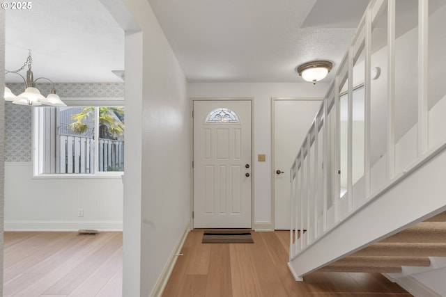 entryway featuring an inviting chandelier, a textured ceiling, and light wood-type flooring