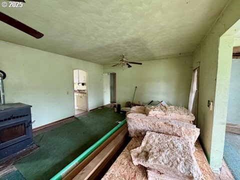 interior space featuring ceiling fan and a wood stove