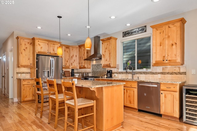 kitchen featuring sink, hanging light fixtures, appliances with stainless steel finishes, a kitchen island, and beverage cooler