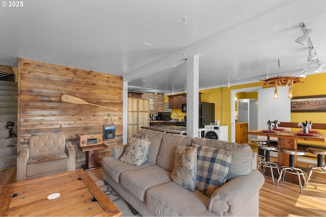 living area with rail lighting, light wood-style floors, and stairs