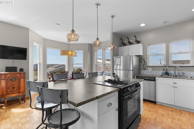 kitchen with a sink, appliances with stainless steel finishes, a breakfast bar, recessed lighting, and white cabinets