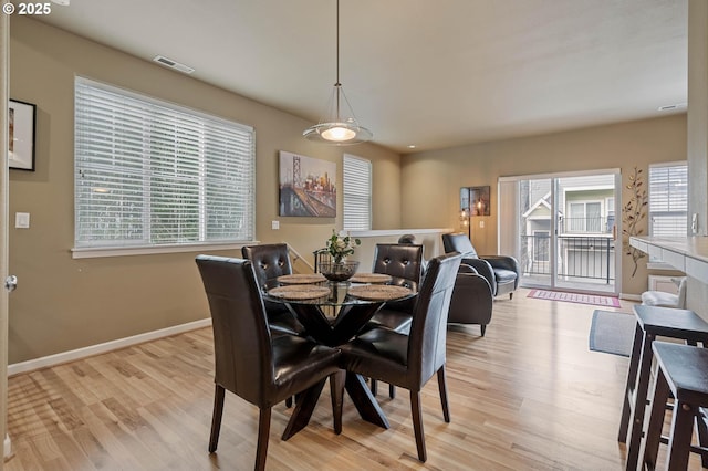 dining room with light wood-type flooring, baseboards, and visible vents