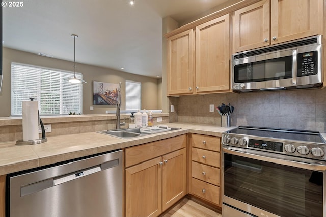 kitchen with decorative backsplash, a peninsula, stainless steel appliances, light brown cabinets, and a sink