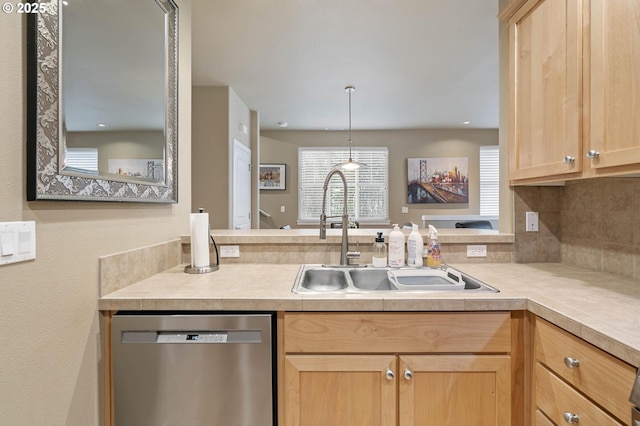 kitchen featuring light countertops, backsplash, light brown cabinets, a sink, and dishwasher